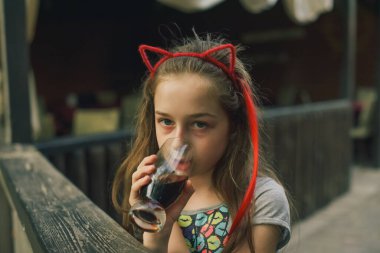 Lokantada içen sevimli, komik küçük kız. Kız bir yaz kafesinde bardaktan içiyor..