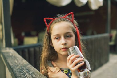 Lokantada içen sevimli, komik küçük kız. Kız bir yaz kafesinde bardaktan içiyor..