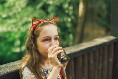 Lokantada içen sevimli, komik küçük kız. Kız bir yaz kafesinde bardaktan içiyor..