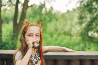 Lokantada içen sevimli, komik küçük kız. Kız bir yaz kafesinde bardaktan içiyor..