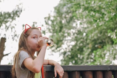 Lokantada içen sevimli, komik küçük kız. Kız bir yaz kafesinde bardaktan içiyor..