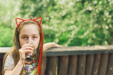 Lokantada içen sevimli, komik küçük kız. Kız bir yaz kafesinde bardaktan içiyor..