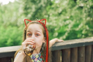 Lokantada içen sevimli, komik küçük kız. Kız bir yaz kafesinde bardaktan içiyor..