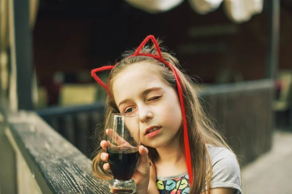 レストランでチャーミング面白い女の子の飲み物 夏のストリートカフェで女の子がガラスから飲む — ストック写真