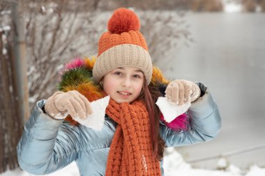 Sıcak elbiseli genç bir kızın kış portresi. Karlı havada şapkalı genç bir kız. Kar yağışıName
