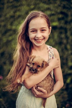 Parkta evcil köpeğiyle gezen sarışın bir kız. Kız yavru köpekleri seviyor. Bir köpek.