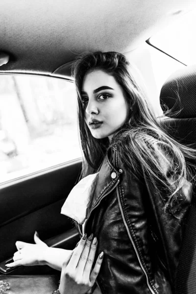 Beautiful young girl rides in a taxi in the back seat. Concept: transport, lifestyle, fashion