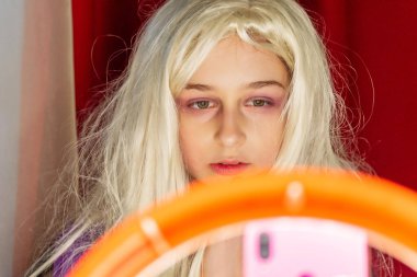 Sosyal medyada, bir güzellik stüdyosunda, halka ışığının önünde selfie çeken bir kız. Gençlik