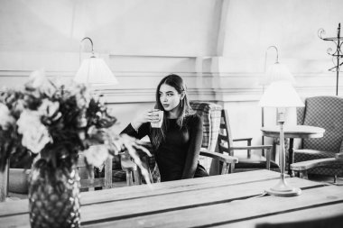 Bir fincan çay ya da kahveli güzel bir kadın. Güzel esmer kız bir kafede tahta bir masada oturuyor.