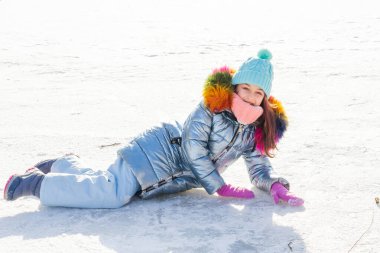 Şapkalı ve mavi ceketli kız. Okul çocuğu, kışlık giysiler içinde sokakta. Kışın çocuk karlı