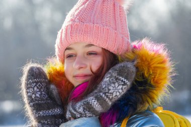 Sıcak elbiseli bir kızın kış portresi. Pembe şapkalı ergen kız. Karlı havada ergen.