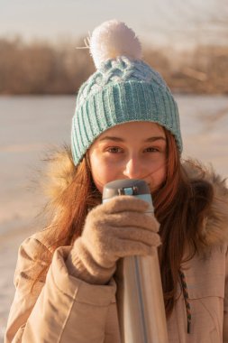 Kışın termostan su içen genç bir kız. Kışın termostan çay içen bir kız.