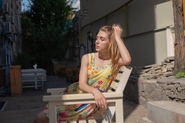 Elbiseli kız yazın eski kasabada yürür. Güzel sarışın kadın yaz fotoğrafı..