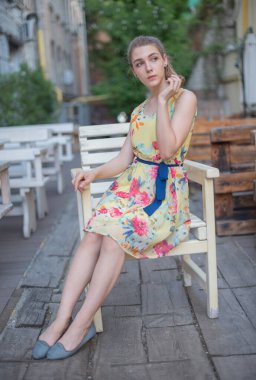 Elbiseli kız yazın eski kasabada yürür. Güzel sarışın kadın yaz fotoğrafı..