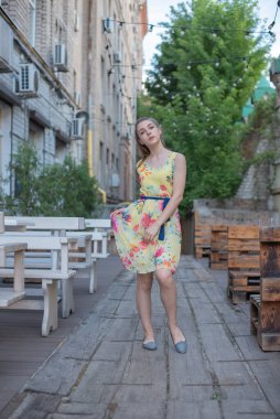 Elbiseli kız yazın eski kasabada yürür. Güzel sarışın kadın yaz fotoğrafı..