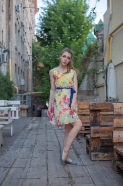 Elbiseli kız yazın eski kasabada yürür. Güzel sarışın kadın yaz fotoğrafı..