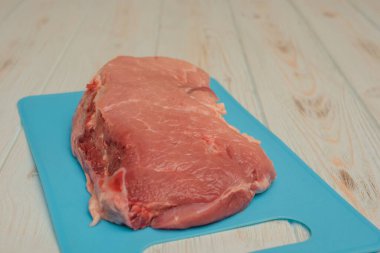 Mavi tahtada çiğ domuz bifteği var. İştah açıcı et. Mavi arkaplanda domuz eti