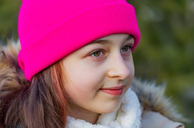 Pembe şapkalı sevimli bir kızın açık hava portresi. Bej ceketli liseli kız. Liseli kız.