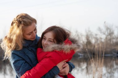 Anne ve kızı hayattan zevk alıyor. Aktif yaşam pozisyonu. Nehir kıyısında aletsiz bir aile zamanı.