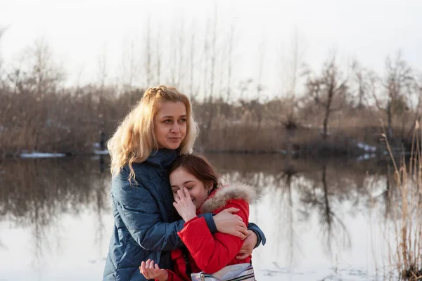 Mom and daughter enjoy life.Active life position. Family time without gadgets in nature by the river