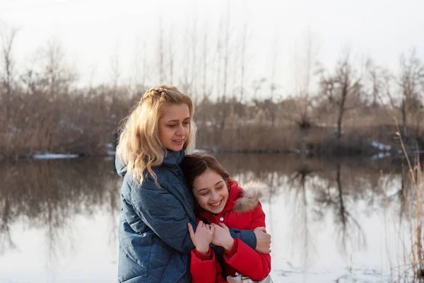 Anne ve kızı hayattan zevk alıyor. Aktif yaşam pozisyonu. Nehir kıyısında aletsiz bir aile zamanı.