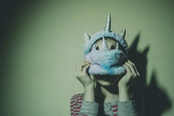 Girl in a unicorn sleep mask. A child in a sleep mask. Teenager girl in pink pajamas at home
