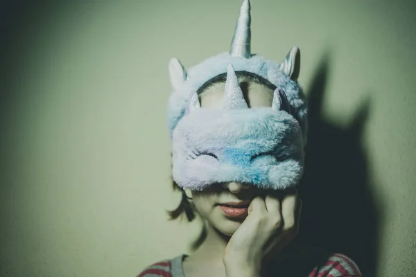 Girl in a unicorn sleep mask. A child in a sleep mask. Teenager girl in pink pajamas at home