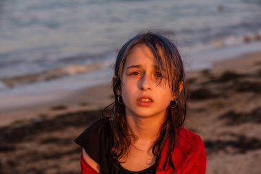 Denizde kırmızı havluyla dolaşan bir kız. Denizde genç bir kız. Dinlenmek, tatil. Deniz kenarında gün batımında.