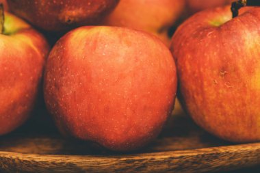 Koyu arkaplanda tahta bir tabakta kırmızı elmalar. Elma kırmızısı ahşap meyve tatlı sağlıklı yemek