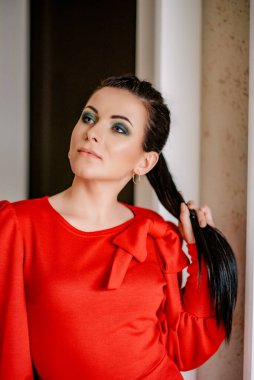 İç kısımda kırmızı elbiseli genç bayan. Kırmızı elbiseli, at kuyruklu esmer kız.