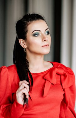 İç kısımda kırmızı elbiseli genç bayan. Kırmızı elbiseli, at kuyruklu esmer kız.