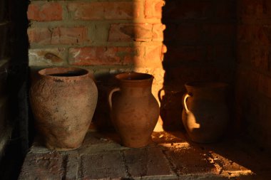 Eski barbekü fırını, eski kil kapları ve taş değirmen taşlarıyla. Ocağın yanında bir sürahi kil.