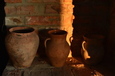 Eski barbekü fırını, eski kil kapları ve taş değirmen taşlarıyla. Ocağın yanında bir sürahi kil.
