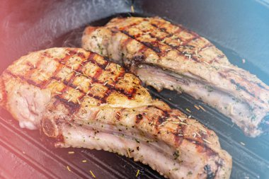 İki büyük domuz bifteği kızartma tavasında kızartılır. Izgara tavada iki domuz eti..