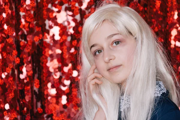 Sarışın. Kırmızı arka plan portresindeki liseli kız. Duygusal kızların bir dizi portresi..