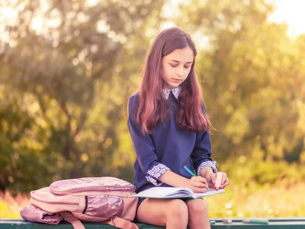 Time to study. Schoolgirl sit bench. Studying in school yard. Smart schoolgirl. Little genius.