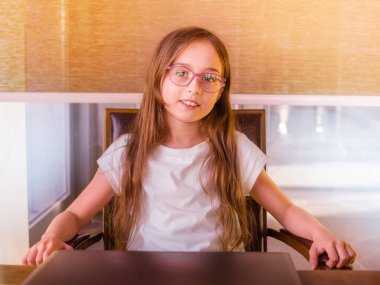 Evde uzak okul eğitimi. 9-10 yaşlarında küçük bir kız çocuğu bilgisayarla ders çalışıyor..
