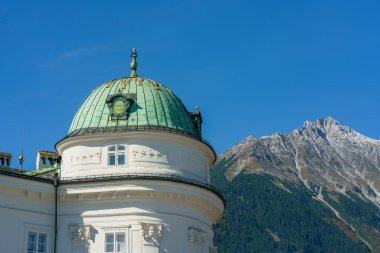 Innsbruck, Avusturya - 11 Ekim 2019: Innsbruck Avusturya 'daki Kaiserliche Hofburg' un (imparatorluk sarayı) yeşil kubbesi aydınlık güneşli bir günde dağ manzarasına karşı
