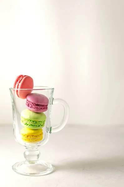 Macarons multicolores dans une tasse en verre sur une serviette en lin. Mcarons ou macarons est un dessert français ou italien. Gros plan. — Photo