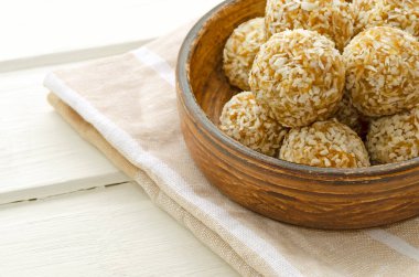 Vejetaryen protein tatlısı, çiğ yulaf ezmesi, meyve parçaları, kurutulmuş meyve, bal, arka planda hindistan cevizi. Seçici odaklanma, metin için yer. Doğal sağlıklı kahvaltı.