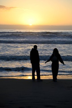 Gençler İtalyan plajında oynuyor. Bazı gençler gün batımında Viareggio plajında oynuyorlar. Bazı gençler cep telefonlarıyla oynuyorlar. Bazı gençler dans ediyor..
