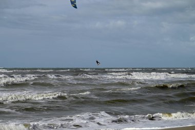 İtalya sahilinde uçurtma. Torre del Lago sahilindeki uçurtmacılar, Toskana, İtalya. Bazıları sudan çıkmakta zorlanıyor. Akdeniz.