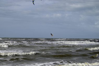 İtalya sahilinde uçurtma. Torre del Lago sahilindeki uçurtmacılar, Toskana, İtalya. Bazıları sudan çıkmakta zorlanıyor. Akdeniz.