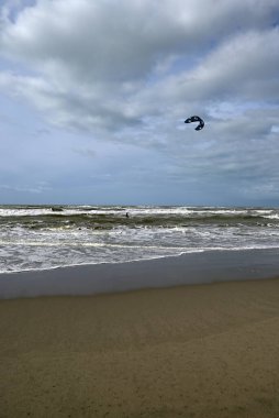 İtalya sahilinde uçurtma. Torre del Lago sahilindeki uçurtmacılar, Toskana, İtalya. Bazıları sudan çıkmakta zorlanıyor. Akdeniz.