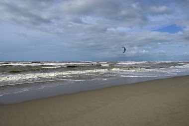 İtalya sahilinde uçurtma. Torre del Lago sahilindeki uçurtmacılar, Toskana, İtalya. Bazıları sudan çıkmakta zorlanıyor. Akdeniz.