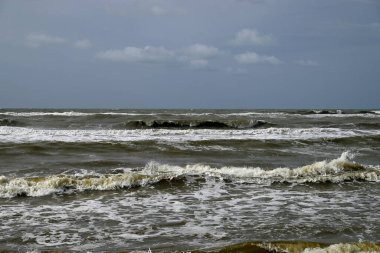 Tore del lago Puccini 'deki Akdeniz Sahili. Küçük güneşli sonbahar gökyüzü. Sudaki yansımalar.