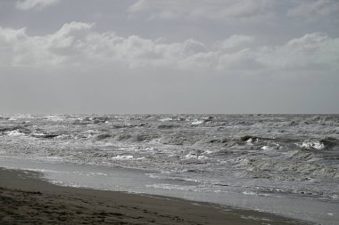 Tore del lago Puccini 'deki Akdeniz Sahili. Küçük güneşli sonbahar gökyüzü. Sudaki yansımalar.