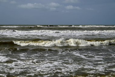 Tore del lago Puccini 'deki Akdeniz Sahili. Küçük güneşli sonbahar gökyüzü. Sudaki yansımalar.