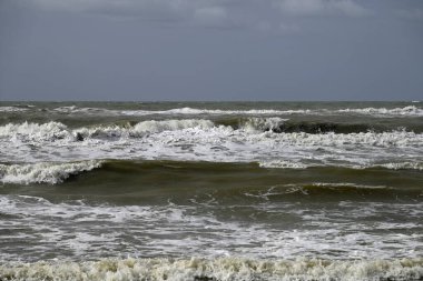 Tore del lago Puccini 'deki Akdeniz Sahili. Küçük güneşli sonbahar gökyüzü. Sudaki yansımalar.
