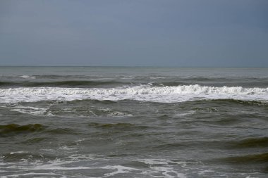 Tore del lago Puccini 'deki Akdeniz Sahili. Küçük güneşli sonbahar gökyüzü. Sudaki yansımalar.